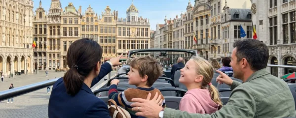 Une famille de quatre personnes vue de dos observe la Grand-Place de Bruxelles depuis l'étage supérieur découvert d'un bus touristique par une journée ensoleillée
